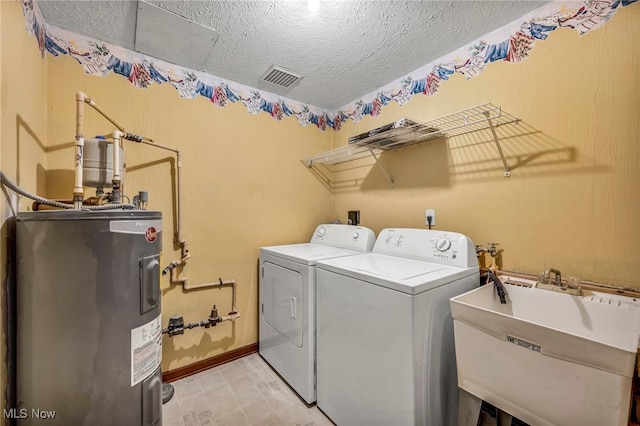 washroom with laundry area, a sink, separate washer and dryer, visible vents, and electric water heater