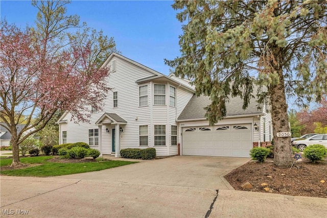 traditional-style home with a garage, a shingled roof, and driveway