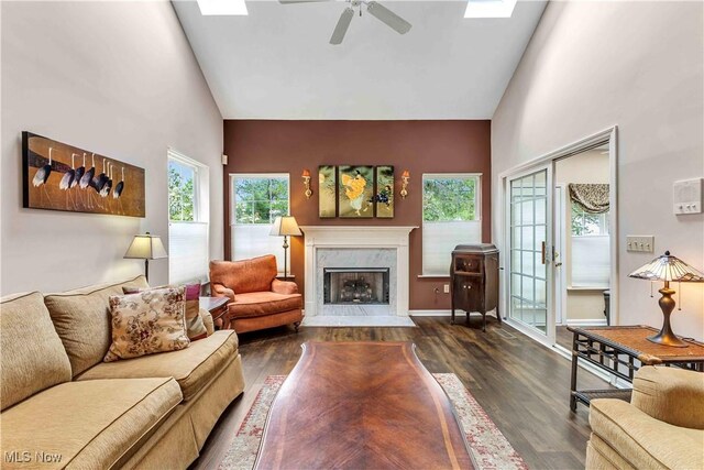living area featuring high vaulted ceiling, a fireplace, a ceiling fan, and wood finished floors