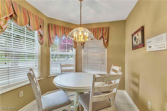 dining space with baseboards, tile patterned flooring, and a notable chandelier