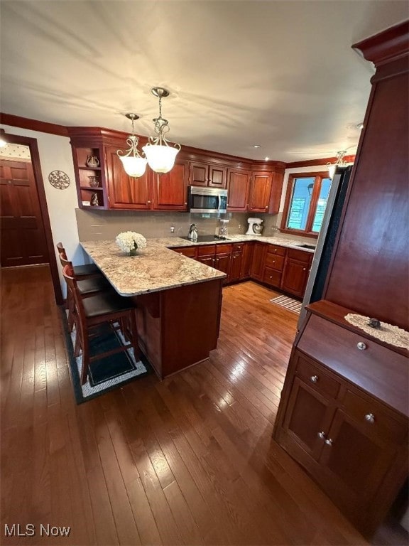422 Glenwoods Ct, Boardman, OH 44512 - kitchen with stainless steel microwave, a peninsula, dark wood-style floors, hanging light fixtures, and crown molding
