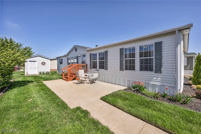 rear view of property with a yard, an outbuilding, and a patio area