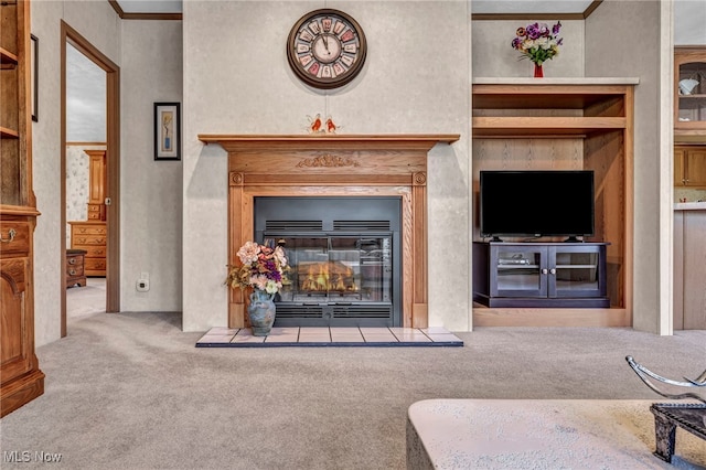 living area with carpet flooring, a glass covered fireplace, and ornamental molding