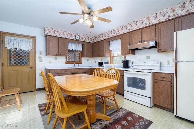 kitchen with white appliances, light countertops, a ceiling fan, light floors, and under cabinet range hood