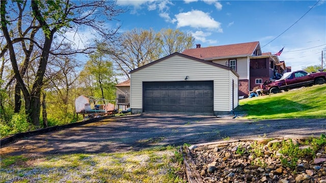 view of side of property with a garage, an outdoor structure, a yard, and driveway