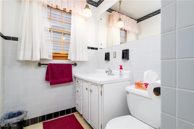 half bathroom featuring toilet, tile patterned floors, tile walls, and vanity