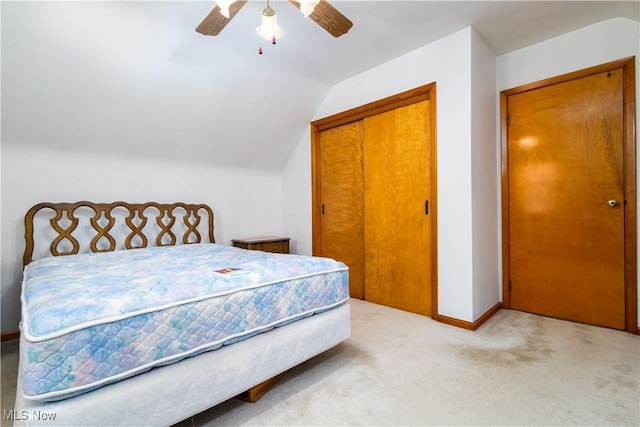 bedroom with ceiling fan, light carpet, baseboards, lofted ceiling, and a closet