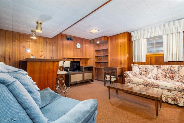 carpeted living room with wood walls and visible vents