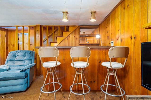 bar with wooden walls, bar, carpet, and stairs