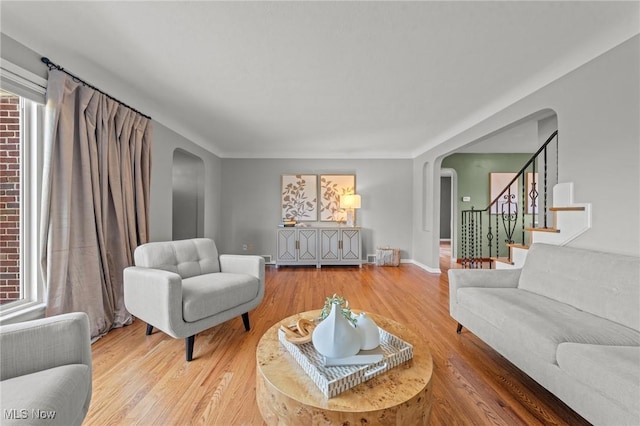 living area with baseboards, arched walkways, wood finished floors, and stairway