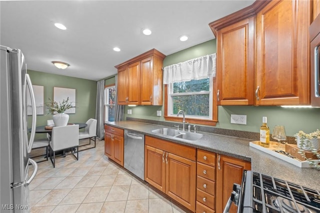 kitchen featuring a sink, appliances with stainless steel finishes, brown cabinetry, and dark countertops