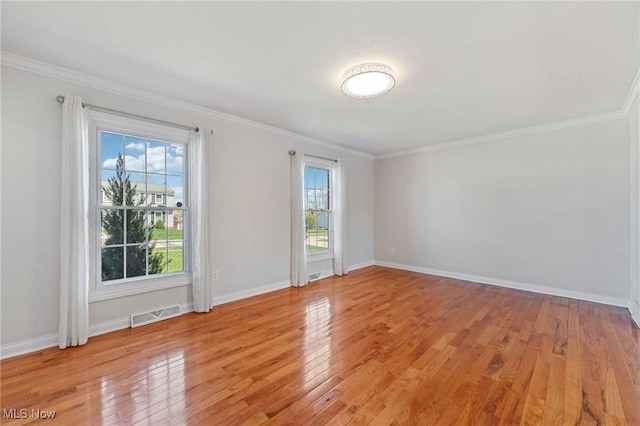 spare room featuring crown molding, baseboards, visible vents, and light wood-style floors