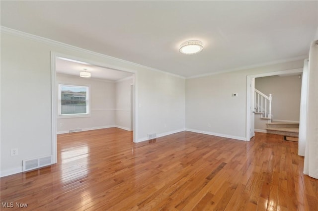 empty room featuring visible vents, ornamental molding, stairway, and light wood-type flooring