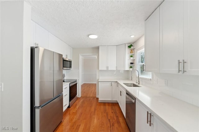 kitchen featuring a sink, a textured ceiling, appliances with stainless steel finishes, and white cabinets