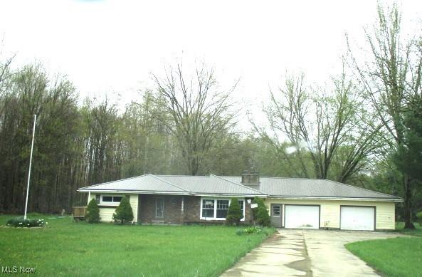 ranch-style house featuring an attached garage, concrete driveway, and a front lawn