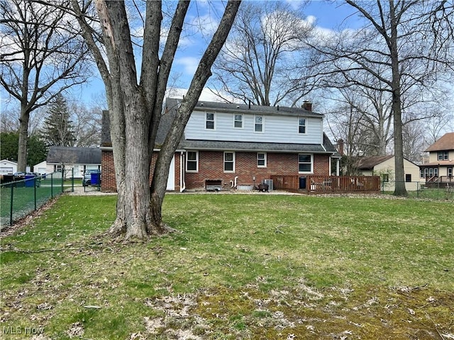 back of house featuring fence, a chimney, brick siding, central AC unit, and a yard