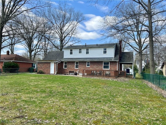 back of house featuring a deck, a fenced backyard, a chimney, brick siding, and a lawn