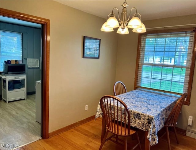 dining space featuring baseboards, a notable chandelier, and light wood finished floors