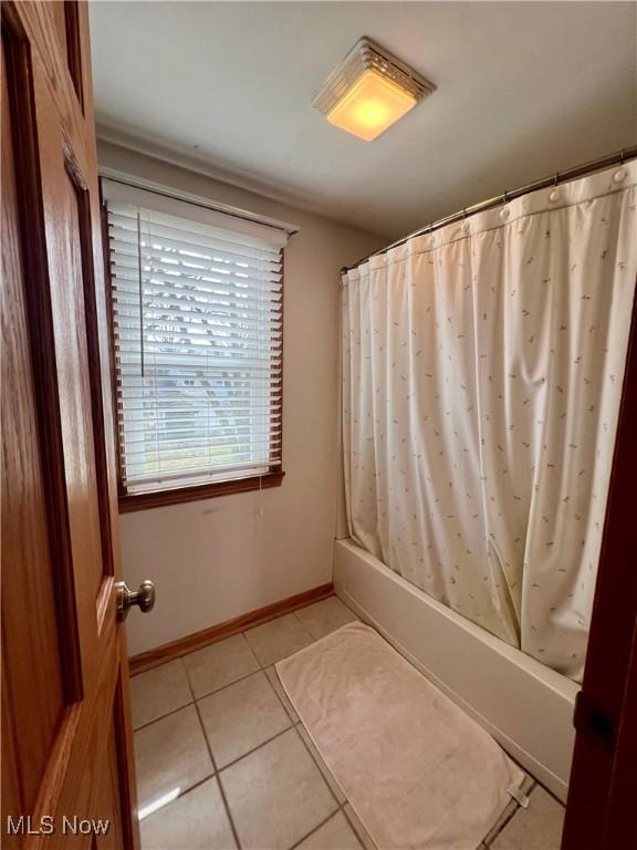 bathroom featuring tile patterned flooring, baseboards, and shower / bath combination with curtain