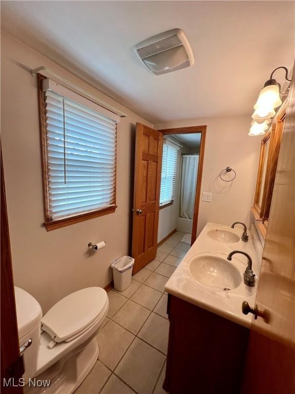 bathroom with a sink, tile patterned flooring, toilet, and double vanity