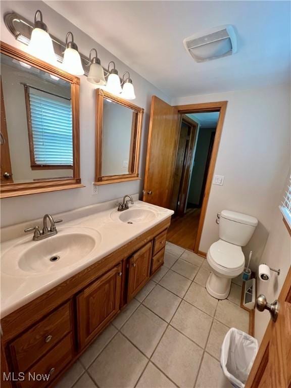 bathroom featuring double vanity, toilet, a sink, and tile patterned flooring