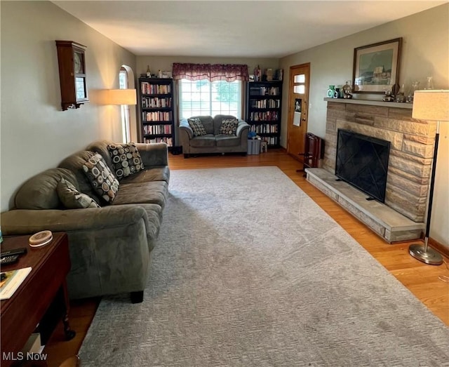 living area with a stone fireplace and wood finished floors