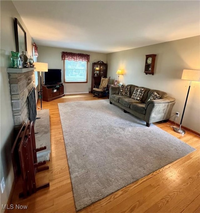 living room featuring light wood-style floors, baseboards, and a fireplace
