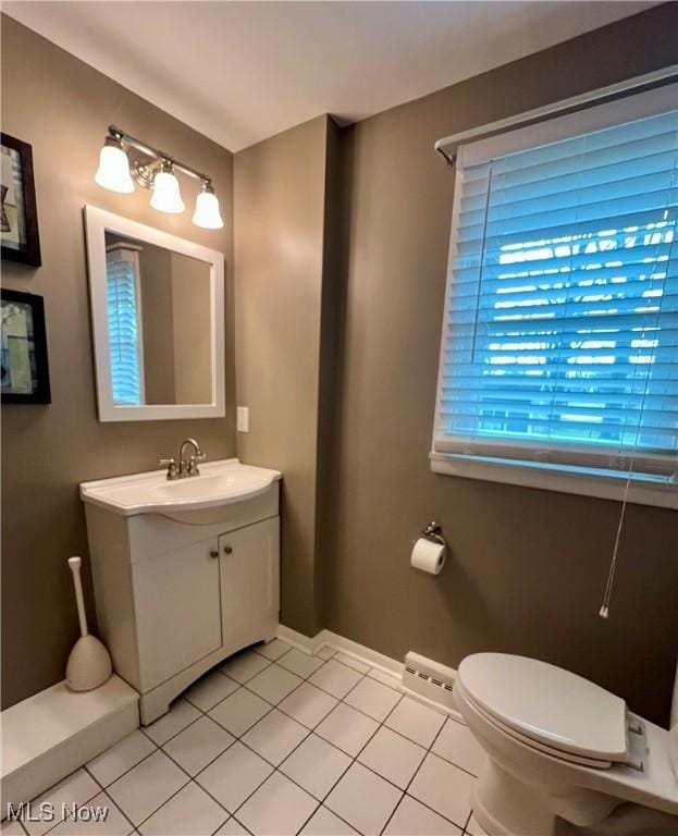 half bath featuring vanity, baseboards, tile patterned floors, and toilet