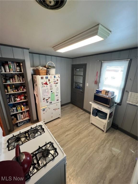 kitchen featuring gray cabinets, light wood finished floors, a decorative wall, and white appliances