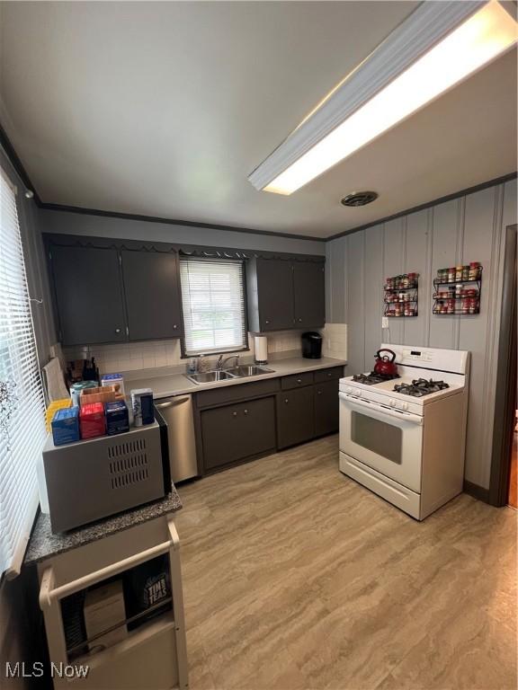 kitchen with white gas range oven, a sink, dishwasher, light countertops, and light wood-style floors