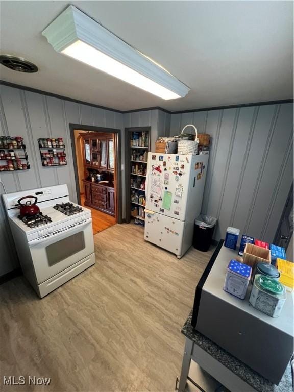 kitchen with white appliances, light wood-style flooring, and a decorative wall