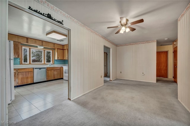 interior space with brown cabinets, a sink, light countertops, a ceiling fan, and stainless steel dishwasher