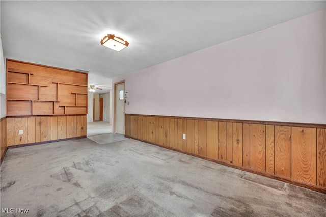 unfurnished room with carpet flooring, wainscoting, and wood walls