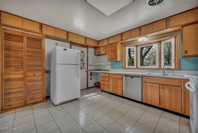 kitchen with visible vents, a sink, light countertops, white appliances, and light tile patterned flooring