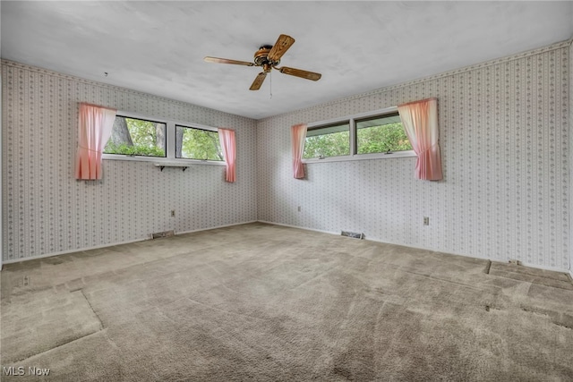 carpeted spare room with ceiling fan, wallpapered walls, and visible vents