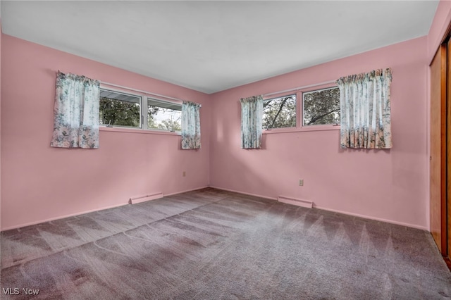 carpeted spare room with baseboards, visible vents, and a wealth of natural light