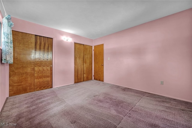 unfurnished bedroom with carpet flooring and multiple closets