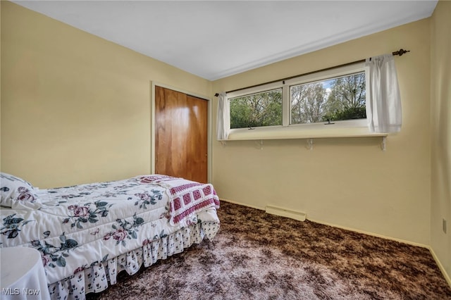 carpeted bedroom featuring baseboards, visible vents, and a closet