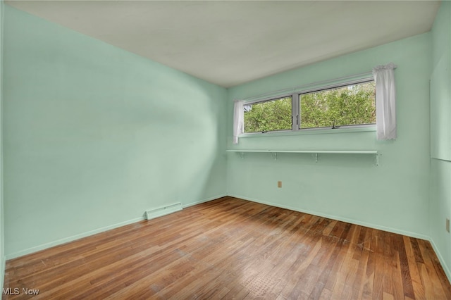 empty room with baseboards, visible vents, and hardwood / wood-style floors