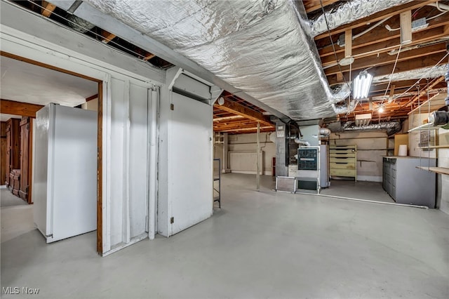 unfinished basement with heating unit and freestanding refrigerator