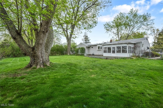 view of yard featuring fence and a sunroom