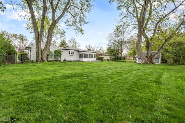 view of yard with a storage shed, fence, an outdoor structure, and a sunroom