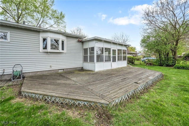 back of property with a sunroom, a lawn, and a deck