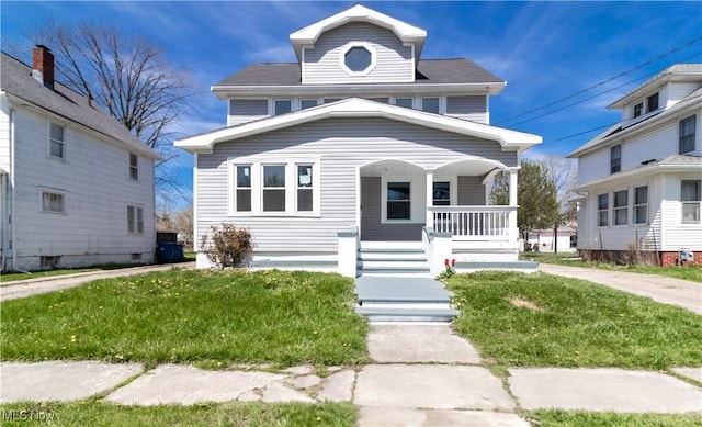 american foursquare style home featuring covered porch and a front lawn
