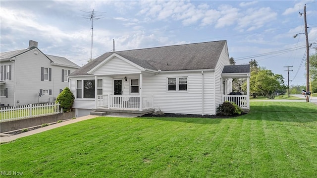rear view of house featuring a porch, roof with shingles, fence, and a yard