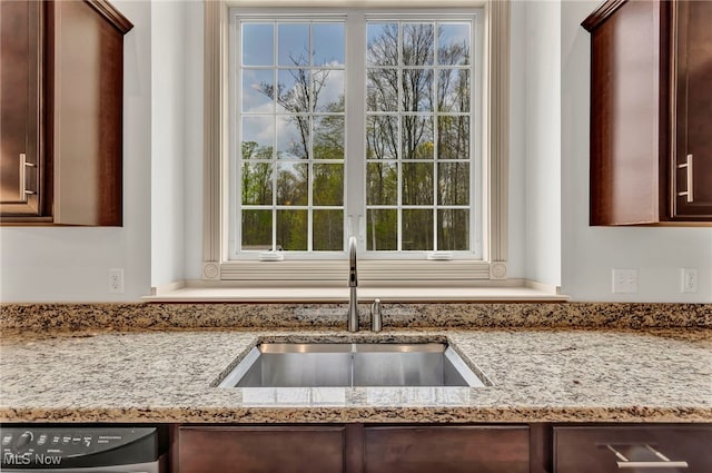 kitchen featuring a sink, dishwasher, dark brown cabinetry, and light stone countertops