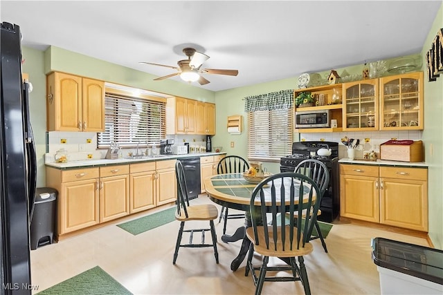 kitchen with light brown cabinets, ceiling fan, tasteful backsplash, a sink, and black appliances