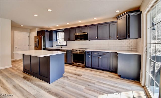 kitchen featuring a sink, decorative backsplash, stainless steel appliances, and light wood-type flooring