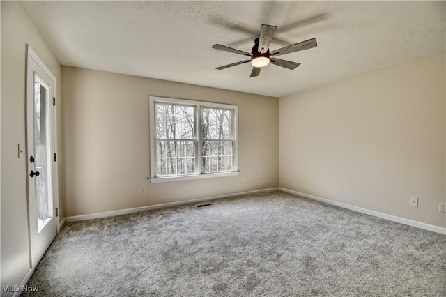 carpeted spare room with baseboards, a ceiling fan, a textured ceiling, and visible vents