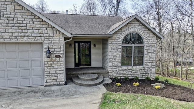 entrance to property featuring an attached garage, a shingled roof, and stone siding